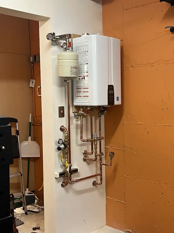 Plumbing technician inspecting water heater connections in Pownal